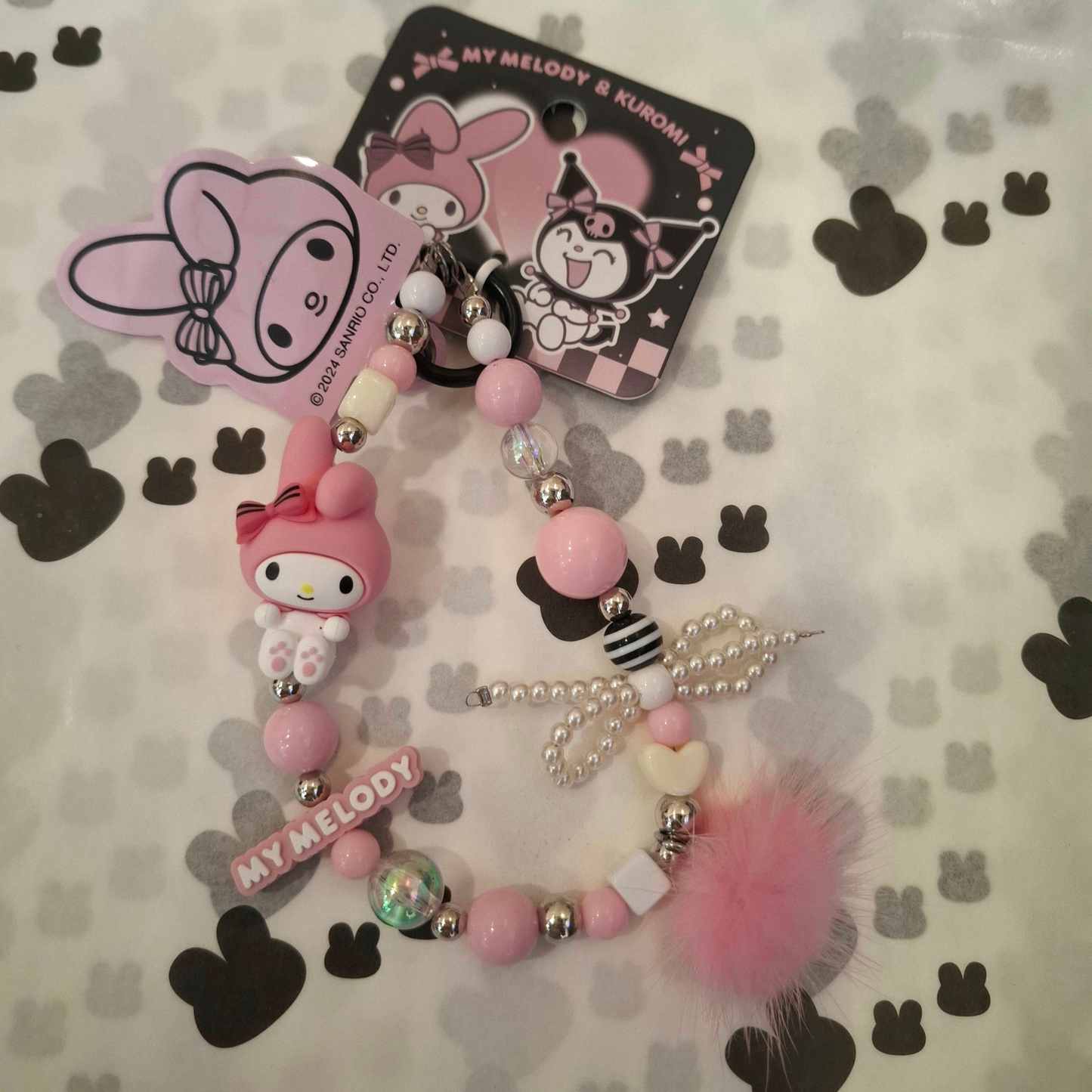 Sanrio – My Melody Telefoonkoord / Phone Strap – Officieel Gelicentieerd – Zachtroze Kawaii Stijl – Met Insteekkaart voor Telefoonhoesje – Luxe Accessoire met Parelstrik, Pluizenbol & Hartjeskralen – Ook als Sleutelhanger of Tassenhanger