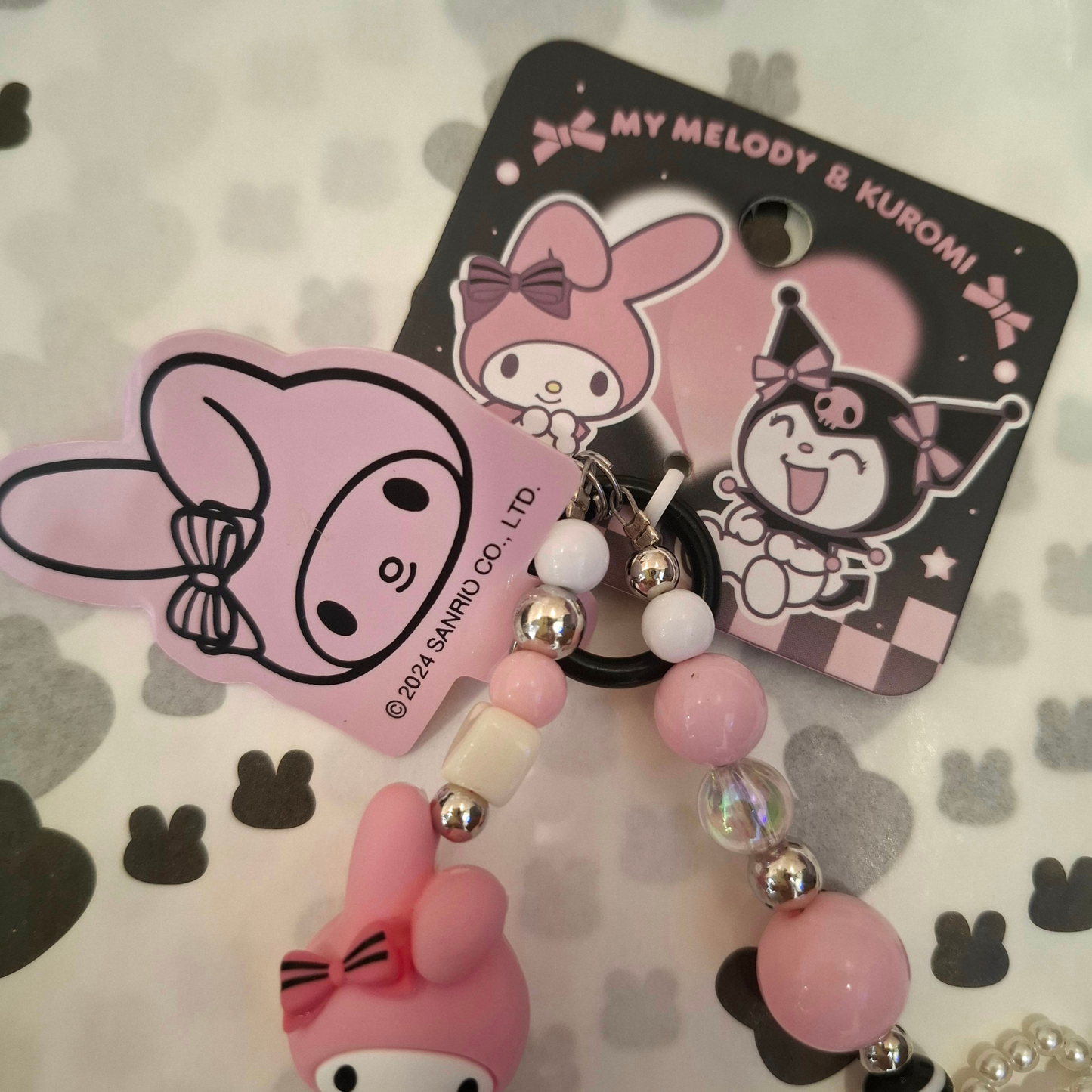 Sanrio – My Melody Telefoonkoord / Phone Strap – Officieel Gelicentieerd – Zachtroze Kawaii Stijl – Met Insteekkaart voor Telefoonhoesje – Luxe Accessoire met Parelstrik, Pluizenbol & Hartjeskralen – Ook als Sleutelhanger of Tassenhanger